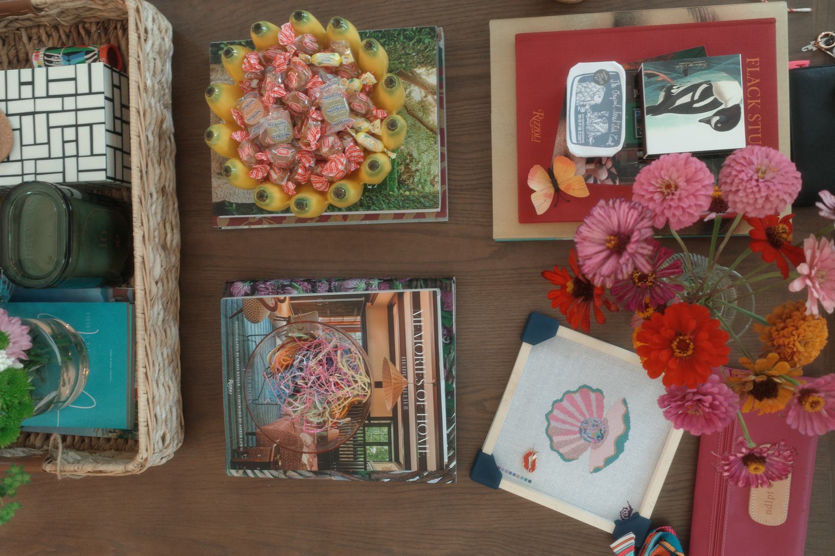 Silk Snail needlepoint canvas styled with design books, zinnias, and studio keepsakes